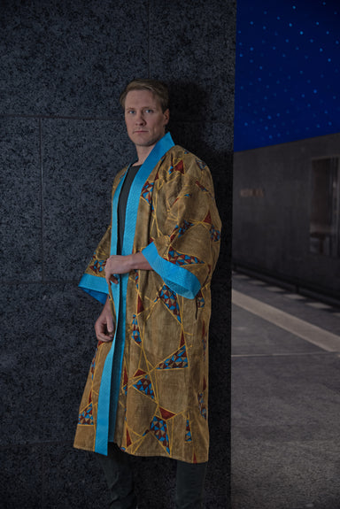 Male model wearing Golden Geometric Kimono (front view), showcasing turquoise blue collar, arm bands, and geometric pattern.