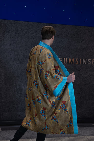 Male model wearing Golden Geometric Kimono (back view), showcasing turquoise blue collar, arm bands, and geometric pattern.