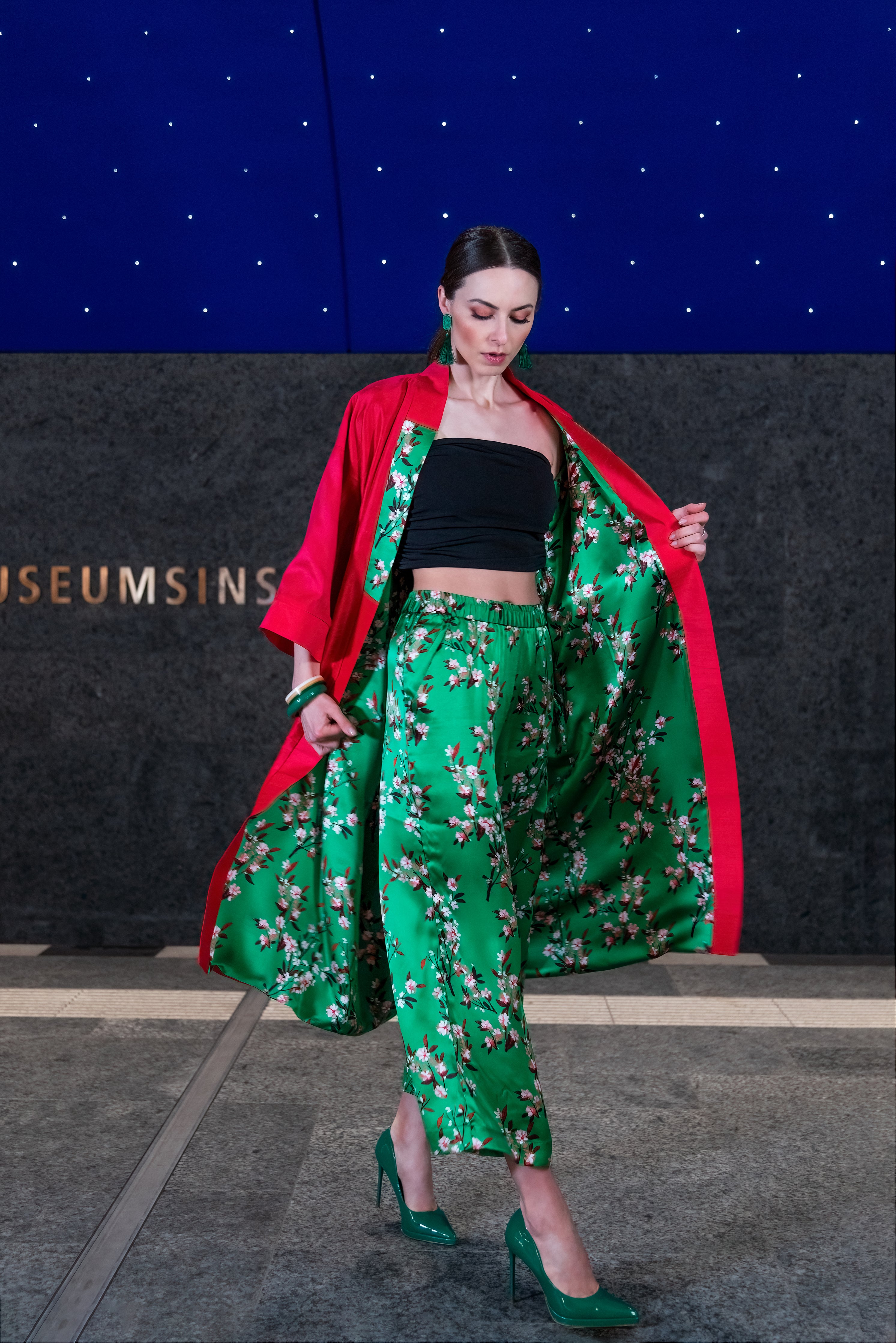 A model walking in the Cherry Blossom Kimono, with the red lining now on the outside, revealing the green fabric underneath as she walks.