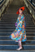 A model stands on stairs, back facing the camera and model looking over her shoulder. The back side of the Kimono is clearly visible. Delicate florals, bursting in a rainbow of colors, adorn the softest mulberry silk.